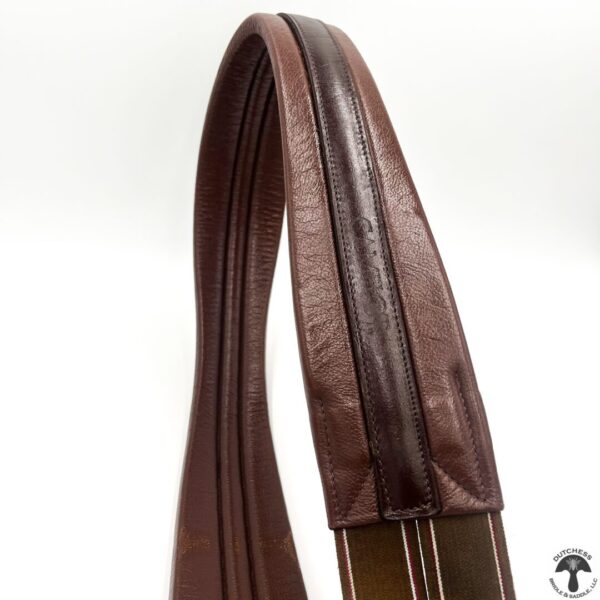 A close up of the side of a brown leather horse bridle.