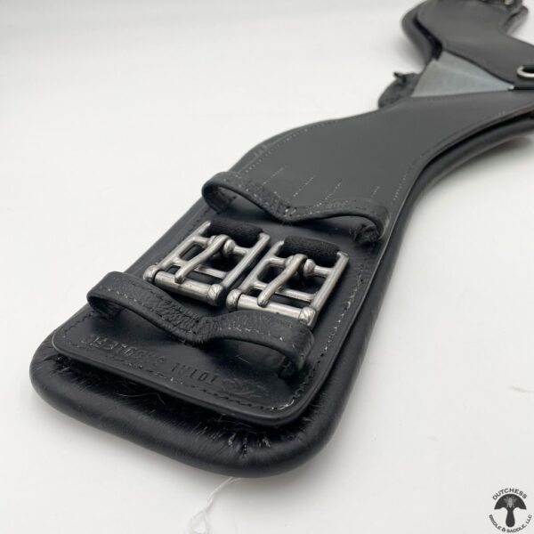 A close up of the handle on a black leather holster.