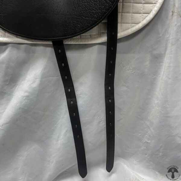 A pair of black leather straps hanging on the side of a white bag.