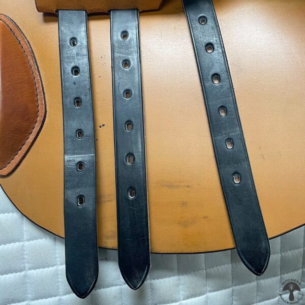 Three black leather straps sitting on top of a table.