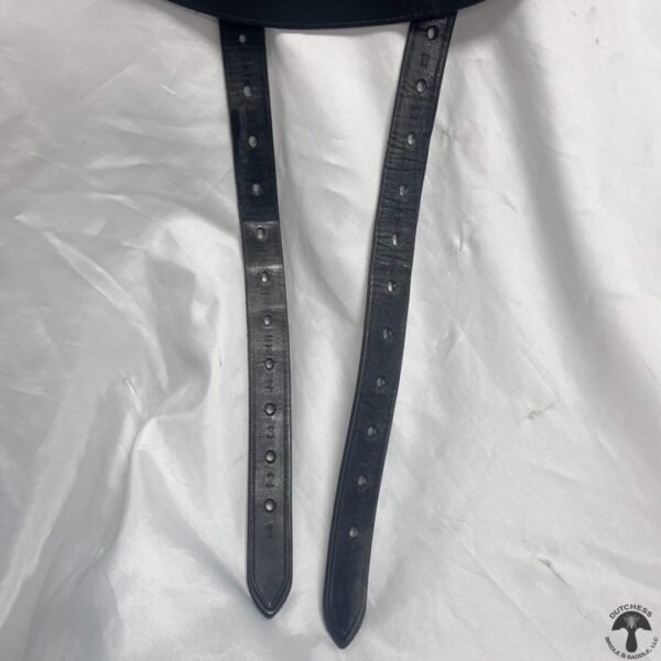 A pair of black leather straps hanging on a white sheet.