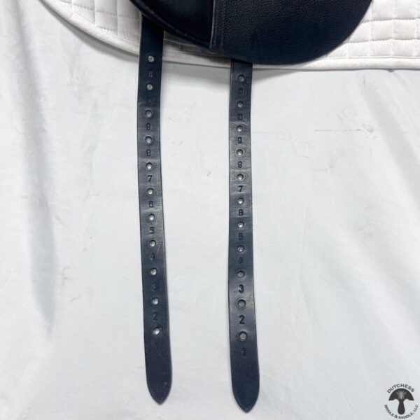 A pair of black leather straps hanging on the side of a white shirt.