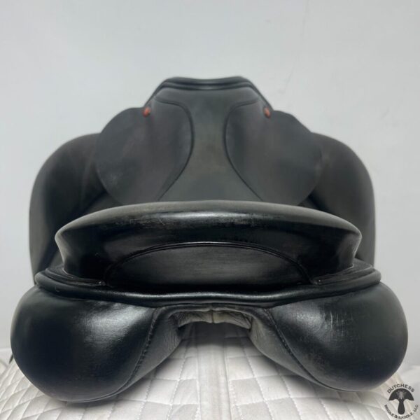 A black saddle sitting on top of a bed.