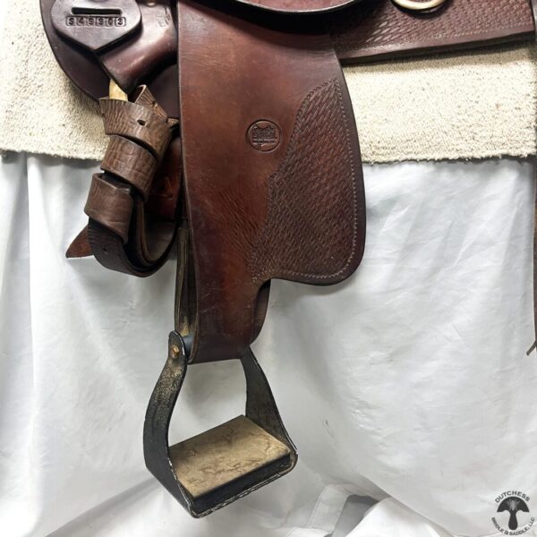 A brown leather saddle hanging on the wall.