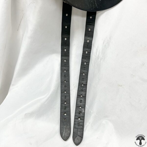 A pair of black leather straps hanging on the wall.