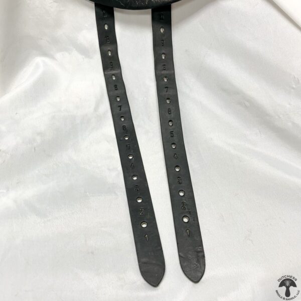 A pair of black leather straps hanging on a white cloth.