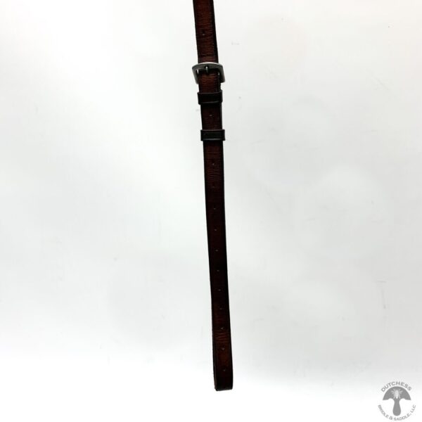 A brown leather strap with silver buckle hanging from the side of a pole.