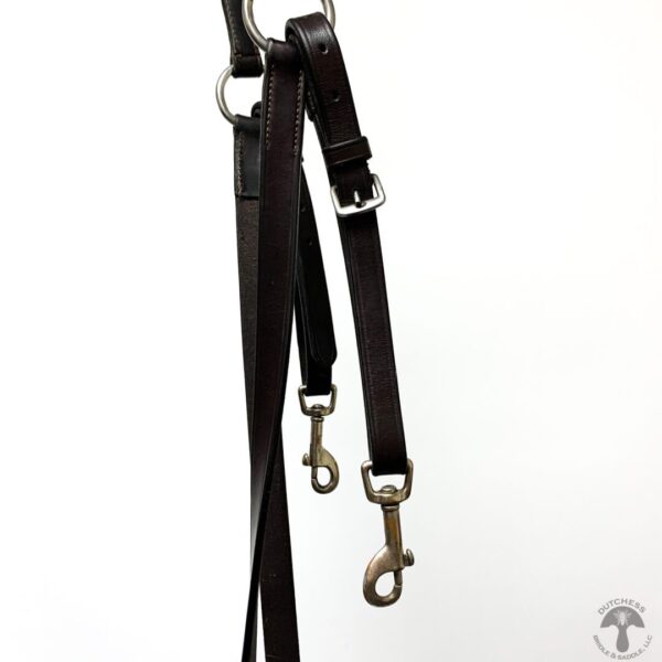 A pair of black leashes hanging on the wall.