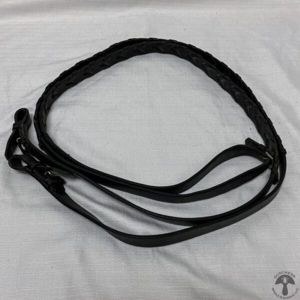 A black leather dog leash laying on top of a bed.