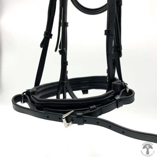 A black bridle and reins on top of a white wall.