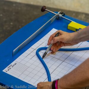 A person cutting paper with scissors and a pencil.