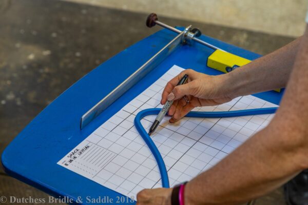 A person cutting paper with scissors and a pencil.