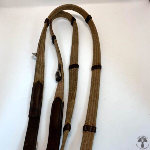 A pair of brown rope leashes hanging on the wall.