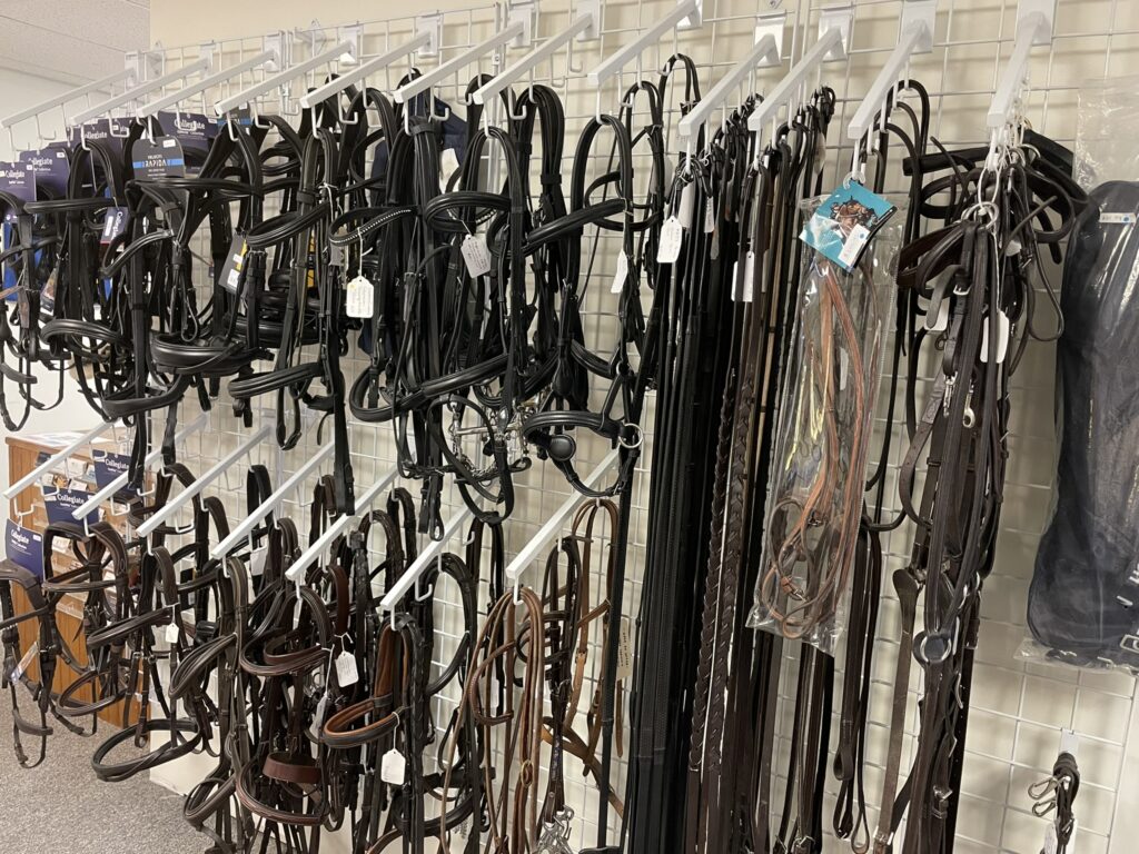 A wall of horse bridles hanging on the side.