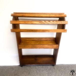 A wooden shelf with three shelves on wheels.