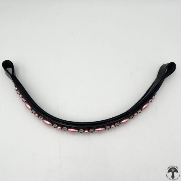 A black and pink leather horse bit with red beads.