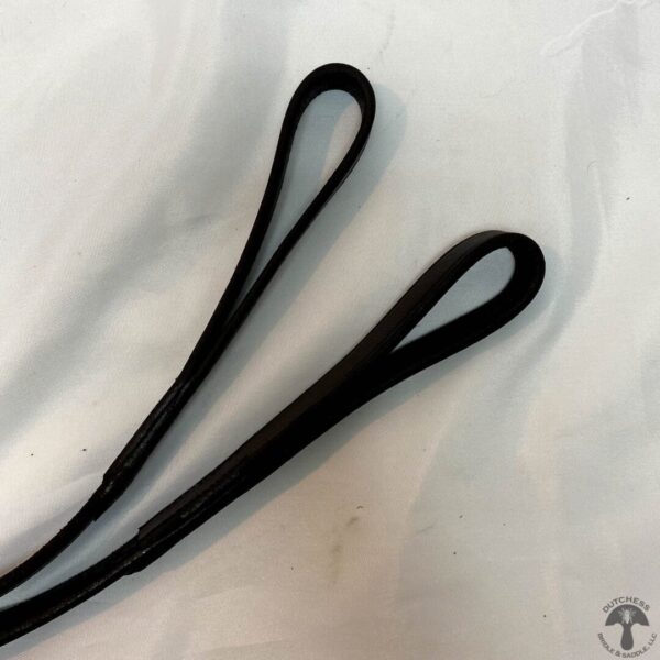 A pair of black hair ties on top of a white sheet.