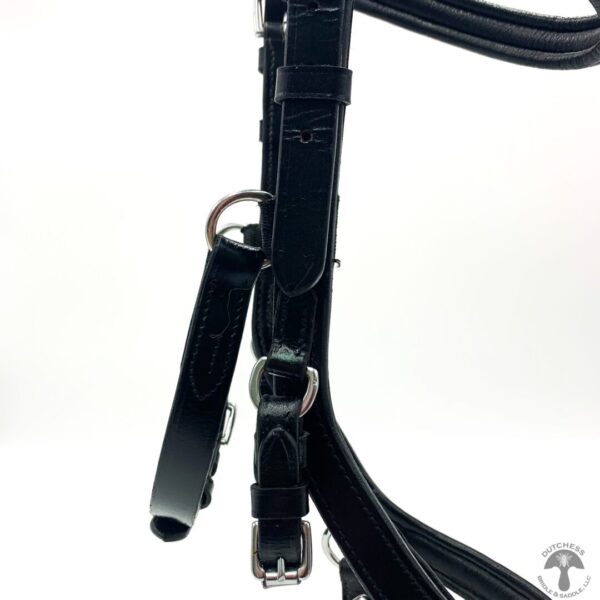 A close up of the bridle and reins on a horse.