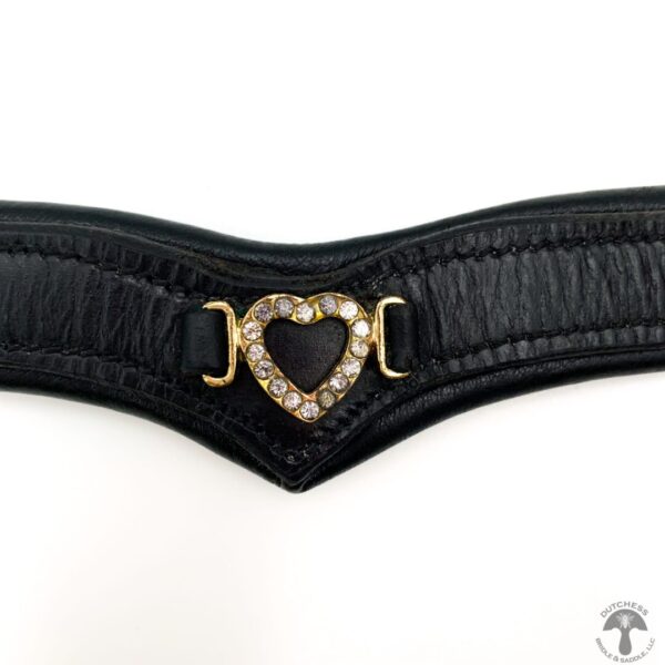 A close up of the heart shaped buckle on a black leather belt.