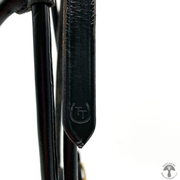 A close up of the strap on a black leather bag