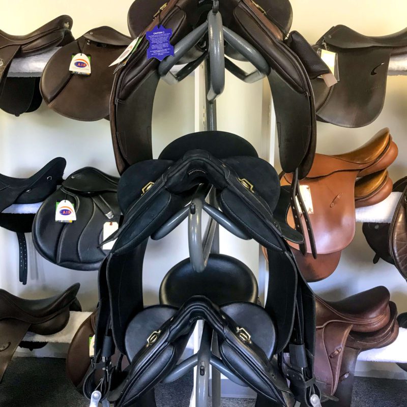 A rack of saddles in different colors and sizes.