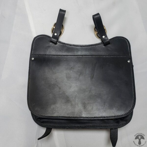 A black leather bag sitting on top of a table.